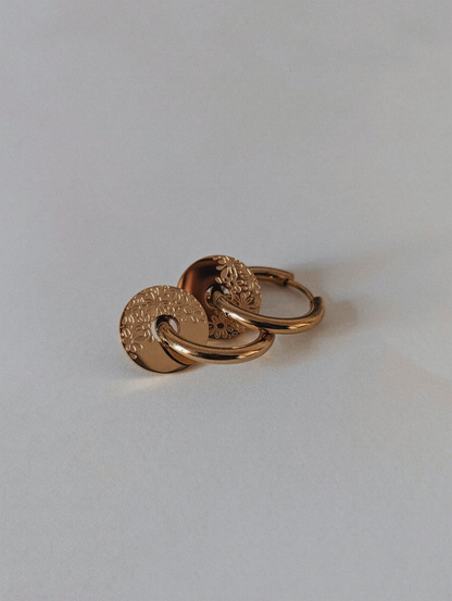 Créoles dorées avec anneaux interchangeables aux motifs fleuris.