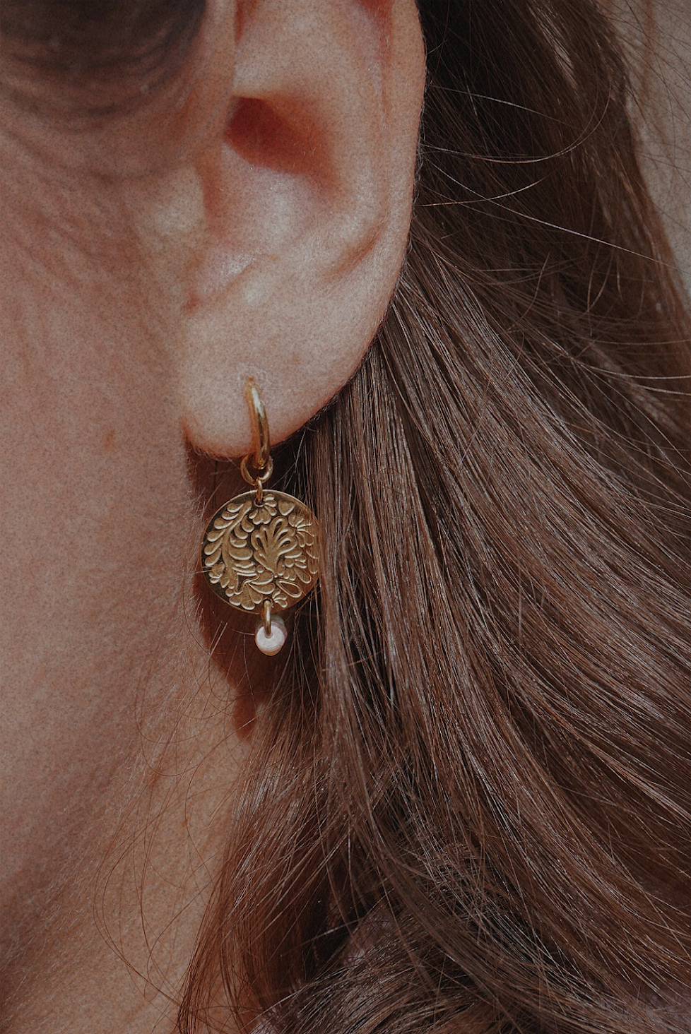 Boucles d'oreilles dorées avec une médaille motifs fleuris et perles multicolores.