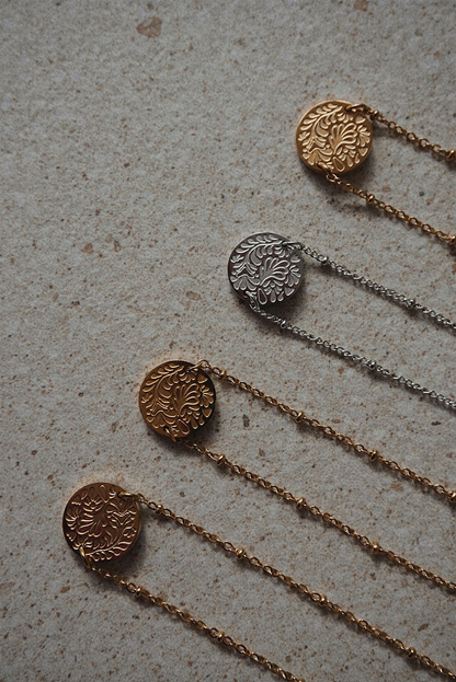 Colliers dorés et argentés avec une médaille aux motifs fleuris.