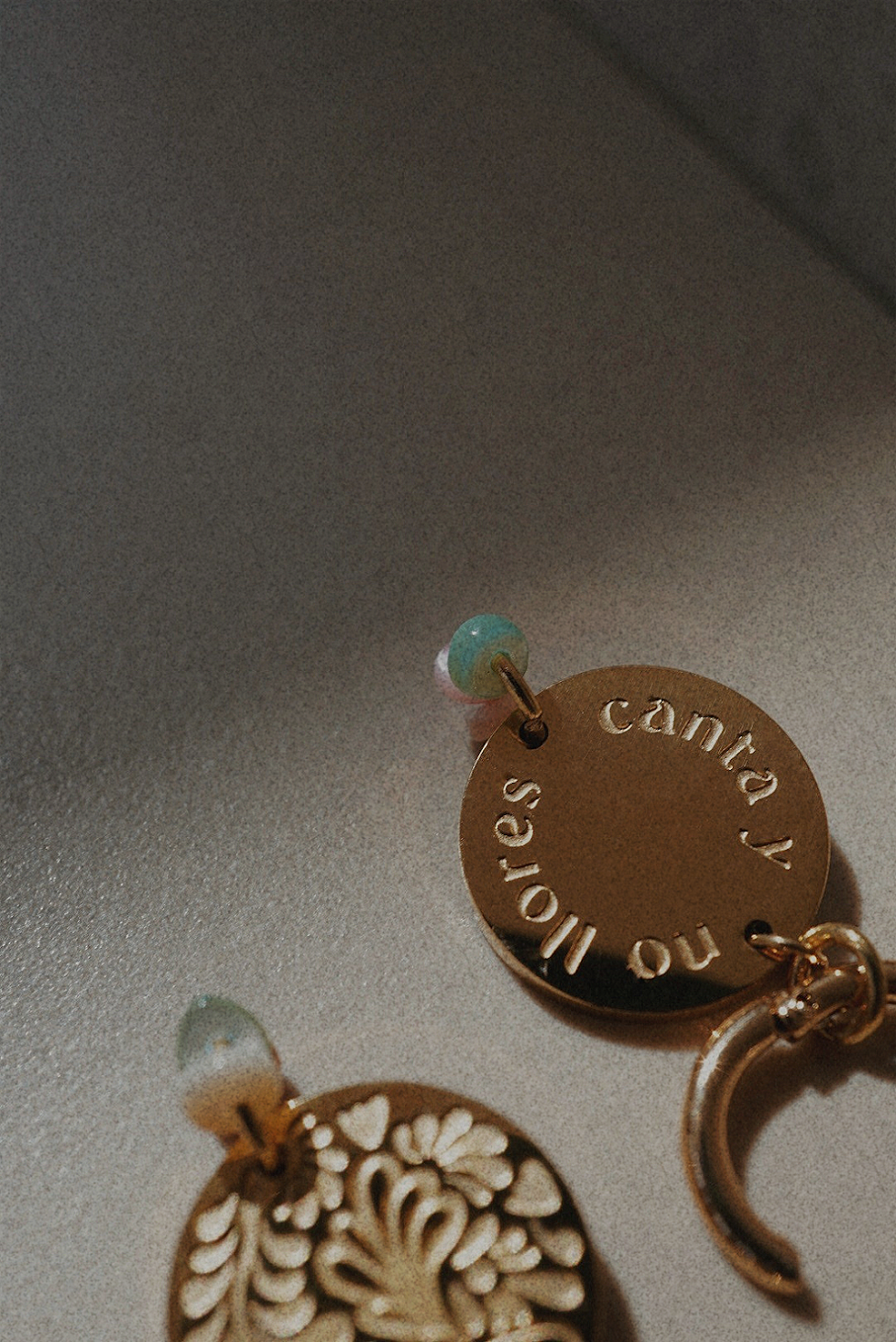 Boucles d'oreilles dorées avec une médaille motifs fleuris et perles multicolores.