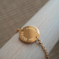 Bracelet doré avec une médaille gravée avec une phrase.