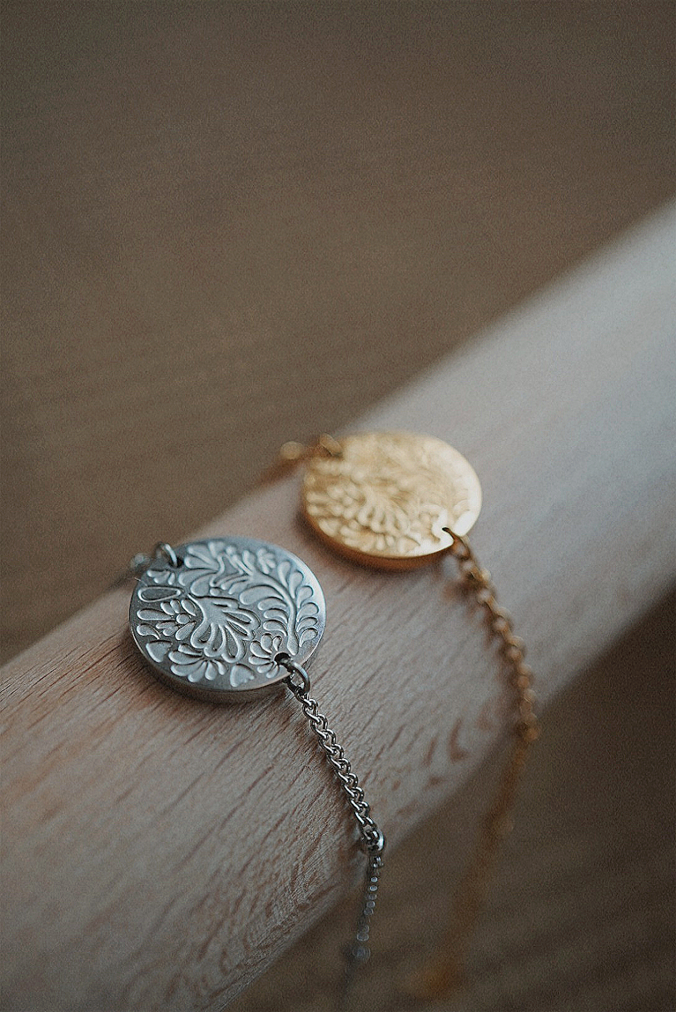 Bracelets dorés et argentés avec une médaille aux motifs fleuris.