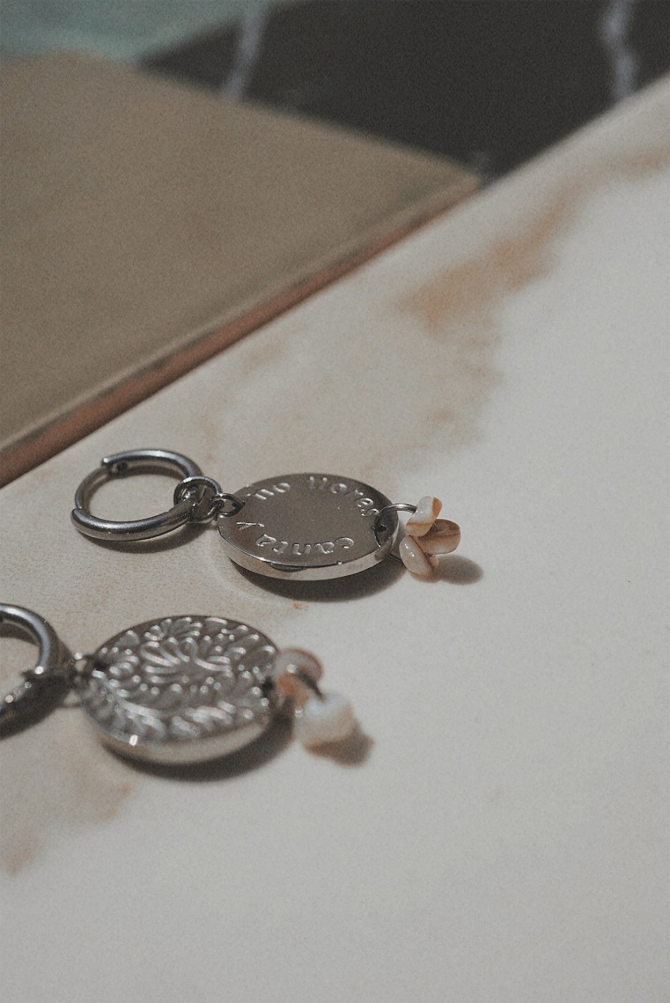Boucles d'oreilles argentées avec une médaille motifs fleuris et perles marrons.